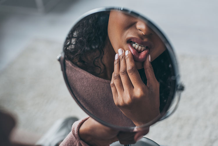 Can bad teeth make you sick? A woman examines her teeth in a mirror, checking for signs of dental issues and oral health concerns.